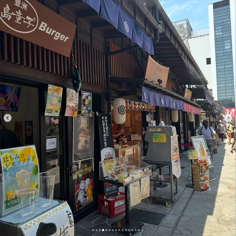 A row of wooden shopfronts with food signs and menus along a pedestrian street.