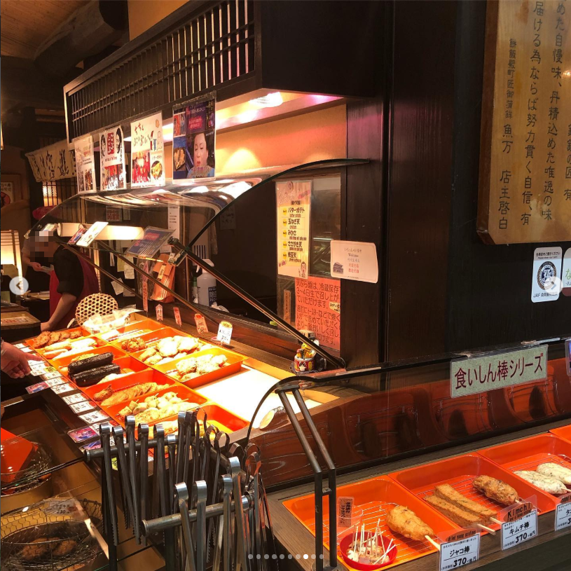 A food stall with wooden panelling and trays of food across the counter.