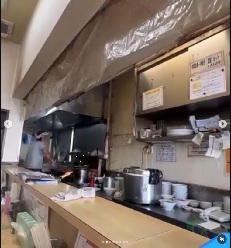 A small counter kitchen with pots, shelves and wall menus.