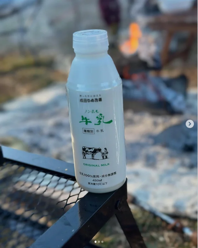 A white drink bottle standing beside an outdoor grill.