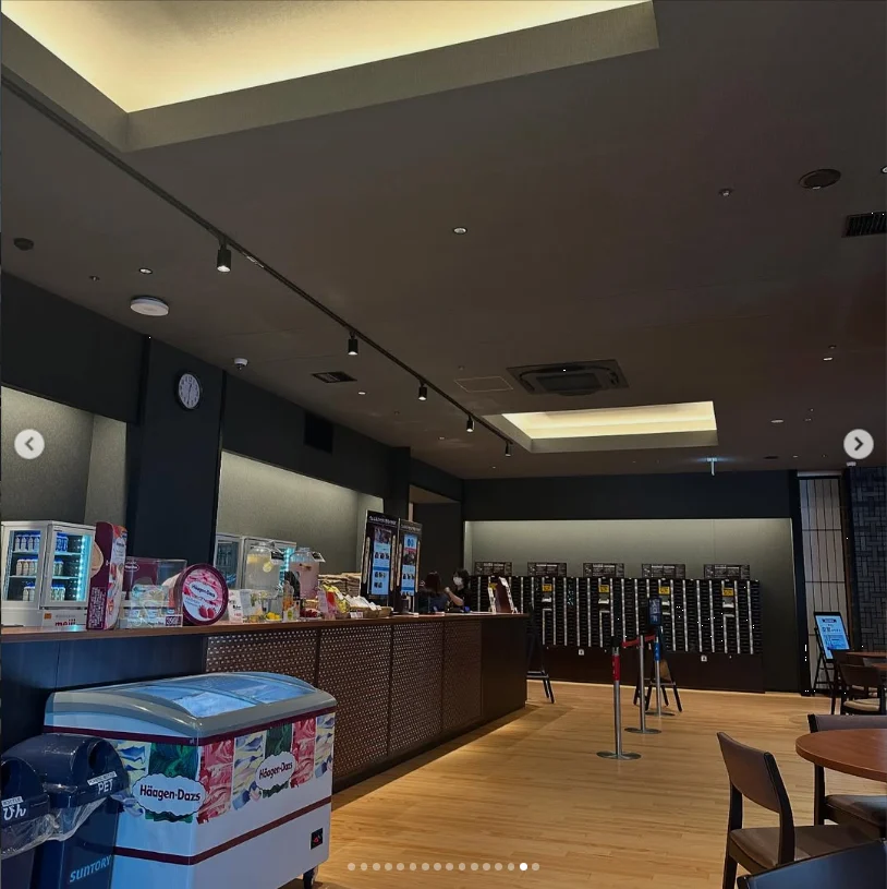 An indoor lobby with a counter, queue ropes, tables and a display freezer.