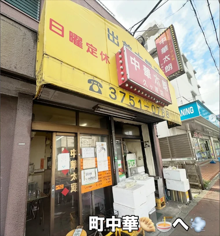 A yellow Japanese restaurant frontage with signs, posters and a delivery scooter outside.