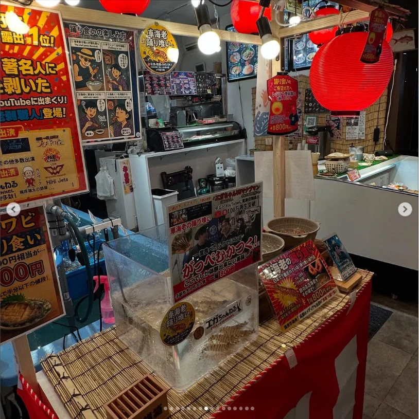 A small food stall with a red lantern, menu posters and a display counter.