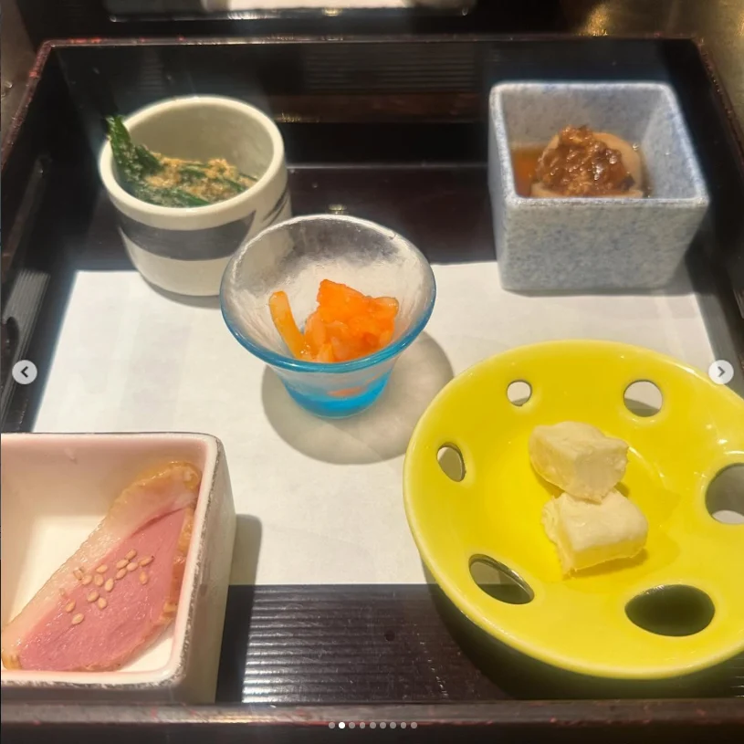 Several small dishes on a tray, including pink slices and a pale piece on a yellow plate.