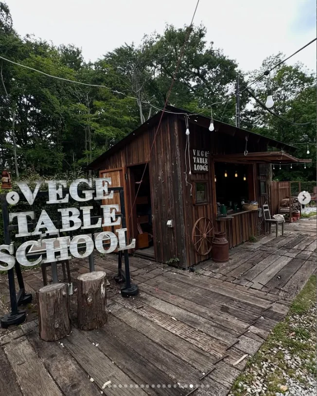 A wooden building with a large outdoor sign, decking and trees behind it.