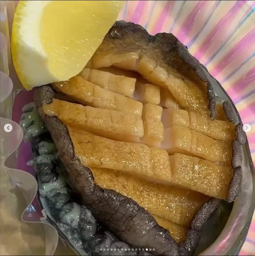 Cross-cut shellfish served in its shell with a lemon wedge.