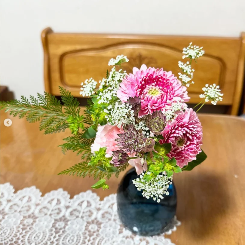 Pink and white flowers with green foliage arranged in a small vase.