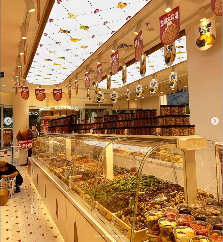 A brightly lit shop interior with a long glass display of small food containers.