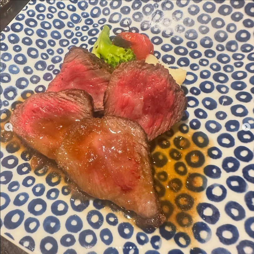 Slices with browned edges and pink centres, with sauce and garnish on a patterned plate.
