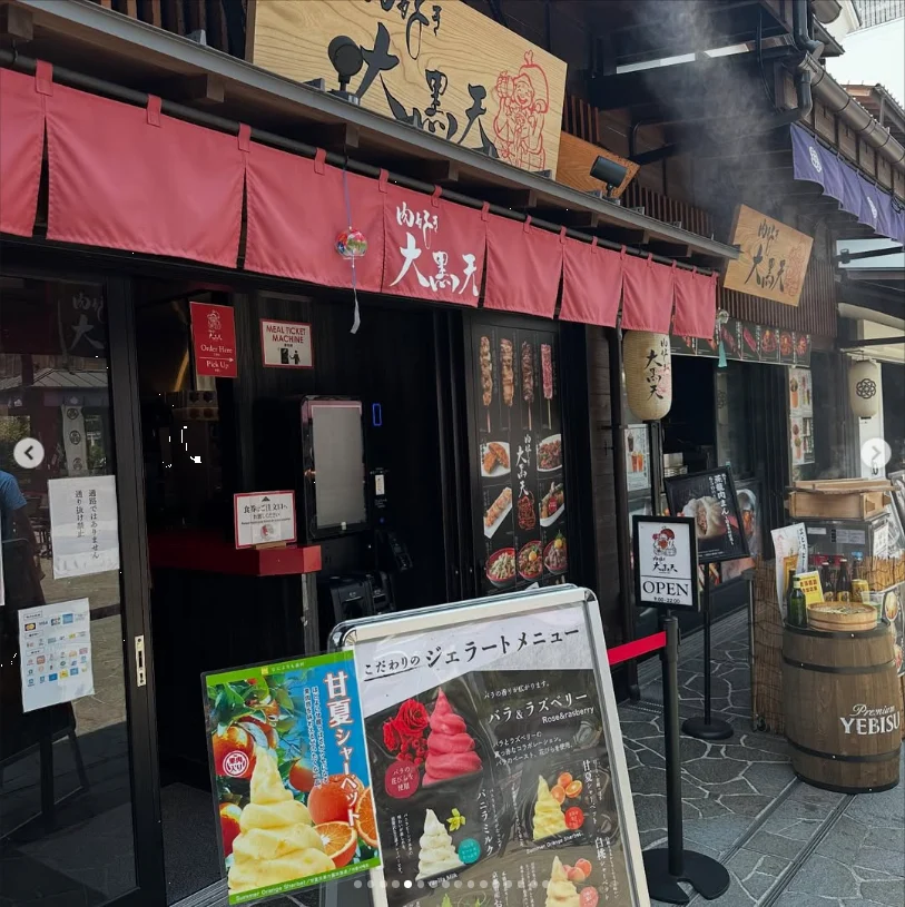 A restaurant frontage with red split curtains and illustrated menu boards outside.