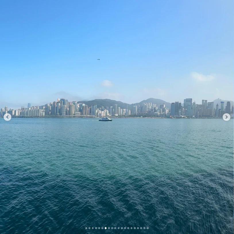 A city skyline across blue water beneath a clear sky.