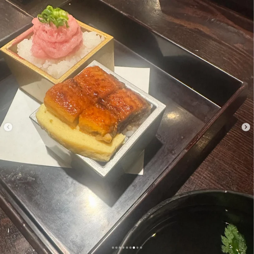 Two small square wooden dishes holding rice topped with pink and golden-brown pieces.