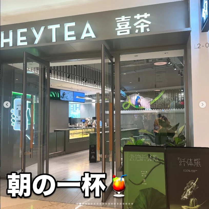 A glass-fronted HEYTEA shop entrance with plants and illuminated signage.