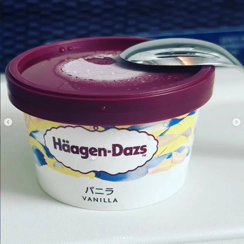 A Haagen-Dazs vanilla cup with a purple lid and a spoon resting on top.